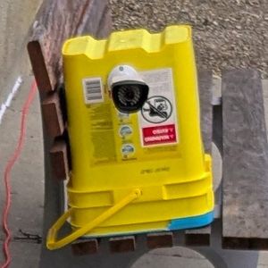 A cat feeder made with a yellow bucket, a silver bucket, and an umbrella